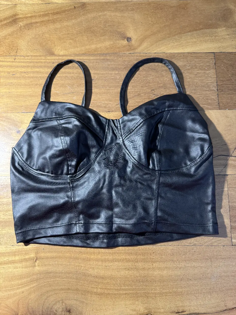 Top negro de cuero sintético con tirantes finos. Ideal para un look audaz y moderno. Perfecto para salir a la noche o para eventos especiales.