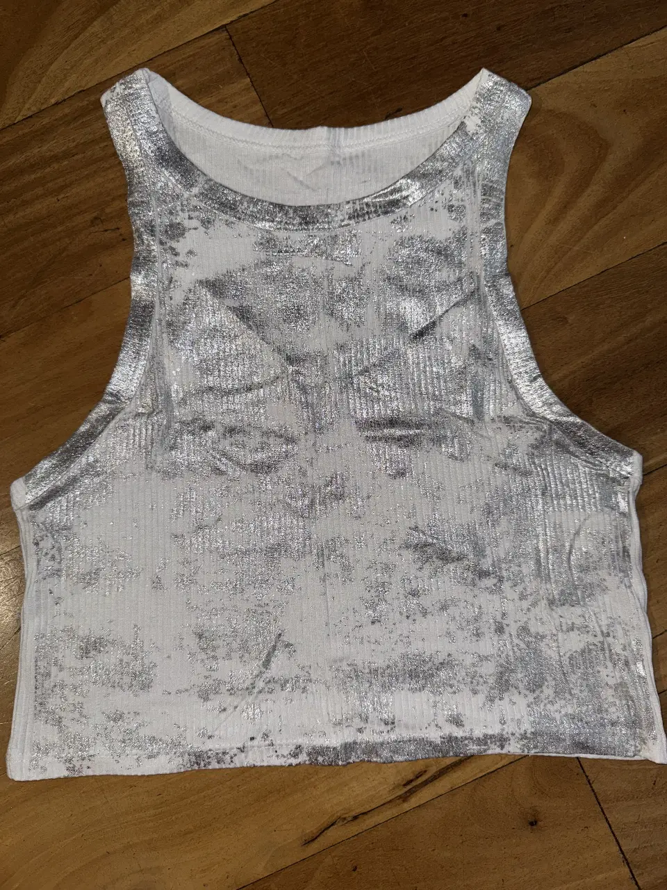 Top blanco con detalles plateados, ideal para un look moderno y canchero. Perfecto para combinar con jeans o shorts.
