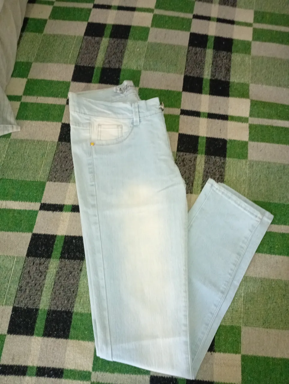 Jeans tiro alto color celeste claro con desgastes sutiles. Presenta bolsillos delanteros y traseros.