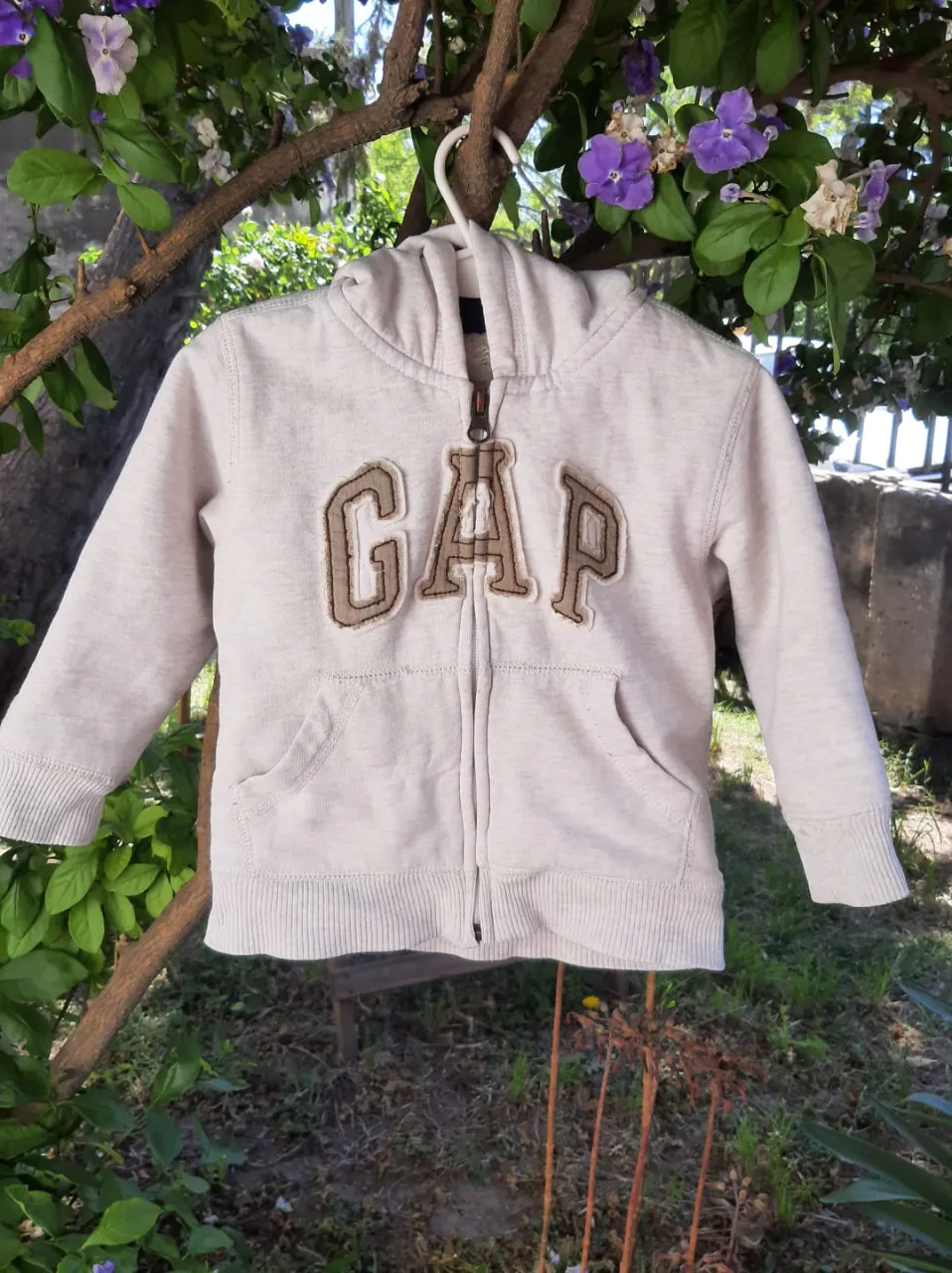 campera unisex con capucha  color gris beige, material de algodón, calidad de excelencia, de la marca Gap,Posee el logo adelante bordado en el frente. Interior forrado en peluche. muy buen estado, talle 2 año, medidas en fotos,