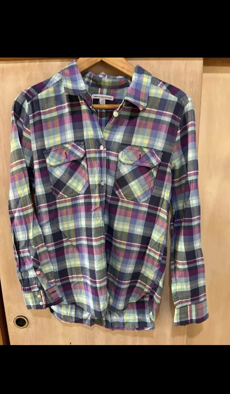 Camisa a cuadros de mujer American Eagle Outfitters, talle XS/TP. Confeccionada en tela liviana, ideal para un look casual y cómodo. Diseño clásico de cuadros en tonos vibrantes.