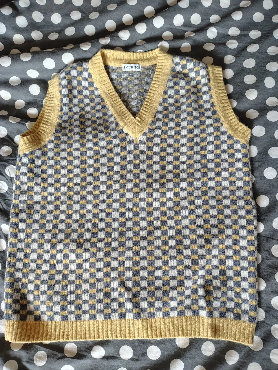 Sweater chaleco de tejido a cuadros en tonos gris, blanco y amarillo. Cuello en V y bordes en amarillo.