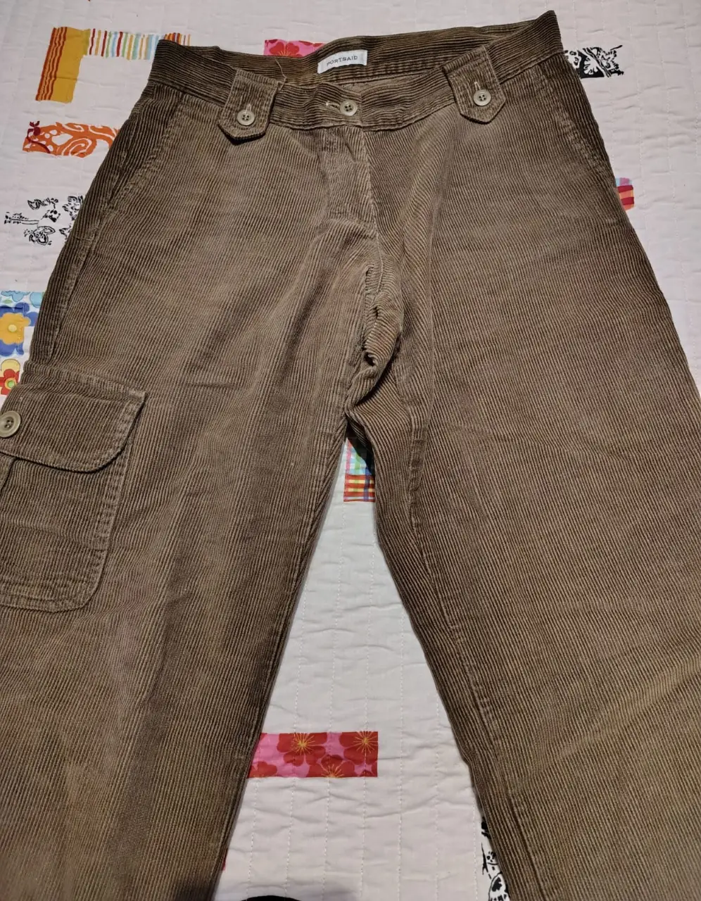 Pantalón cargo de corderoy marrón, tiro alto, con bolsillos laterales y detalle de botones en la cintura. Ideal para un look utilitario y casual.