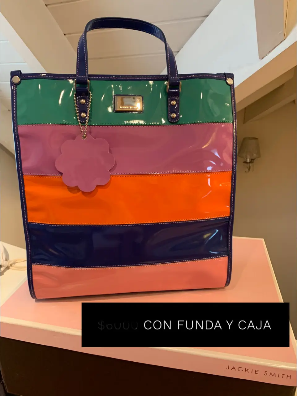 Bolso tote Jackie Smith a rayas en charol, con manijas y detalles en azul. Incluye etiqueta colgante y funda.