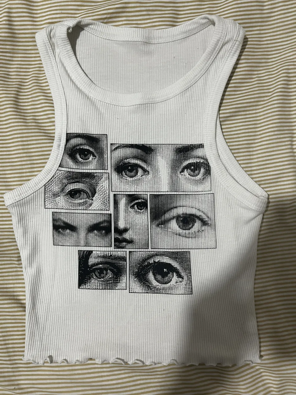 Musculosa blanca con estampa de ojos en la parte delantera. Posee cuello redondo y terminación con volados en la parte inferior.