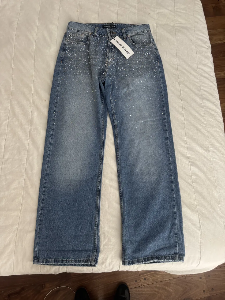 Jeans con strass plateadas en toda la prenda. Cierre y botón.