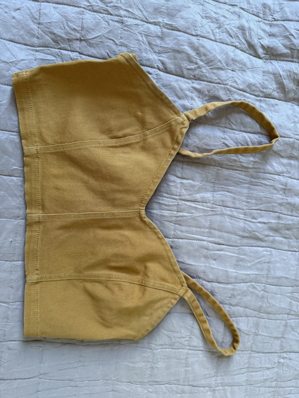 Top color mostaza, con tiras finas y cierre metálico en la espalda. Ideal para un look canchero y moderno.