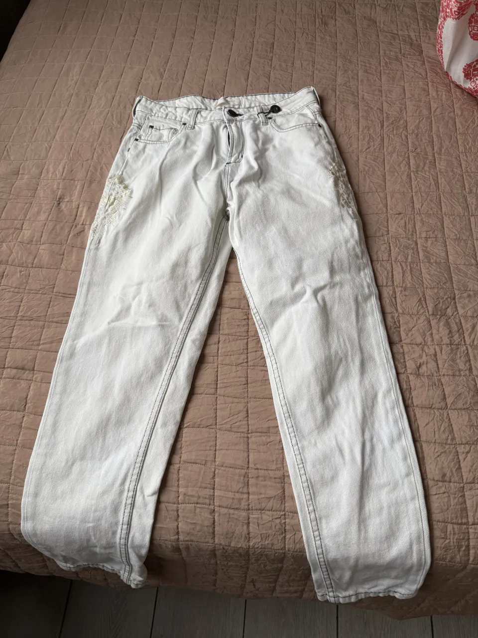 Jeans blancos con bordados en los laterales de los bolsillos delanteros. Costuras visibles en negro. 
Contorno de cintura: 62-66
Contorno de cadera: 94-98