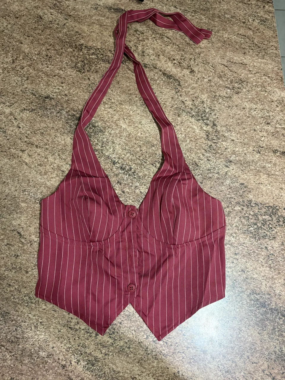Top de morley a rayas verticales en color bordo con detalles en blanco. Posee cuello halter y dos botones en la parte delantera.