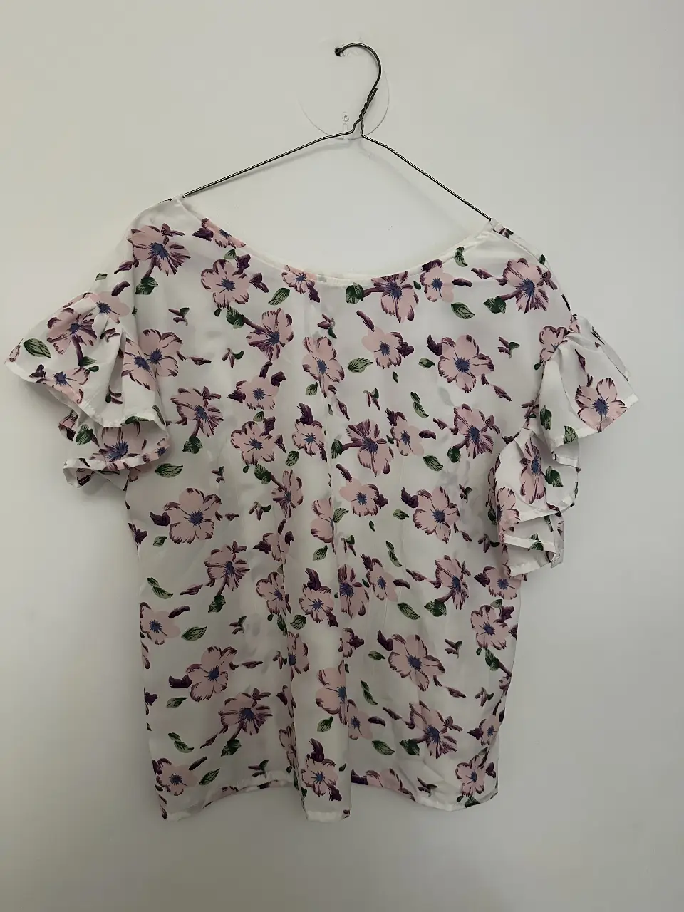 Blusa de mujer con estampado floral en tonos rosa y blanco. Diseño con mangas con volados, ideal para un look fresco y femenino.