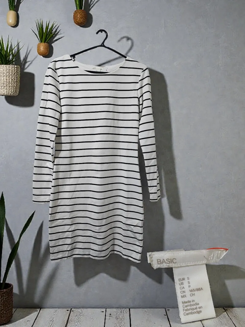 Vestido blanco con rayas negras, manga larga y corte al cuerpo. Ideal para un look casual y cómodo.