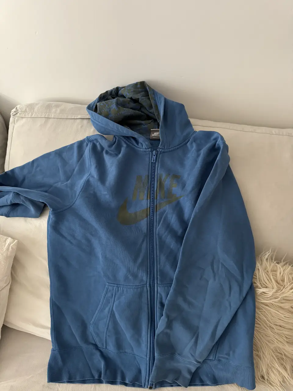 Buzo con cierre Nike azul, con logo en el pecho. Ideal para un look casual y cómodo.