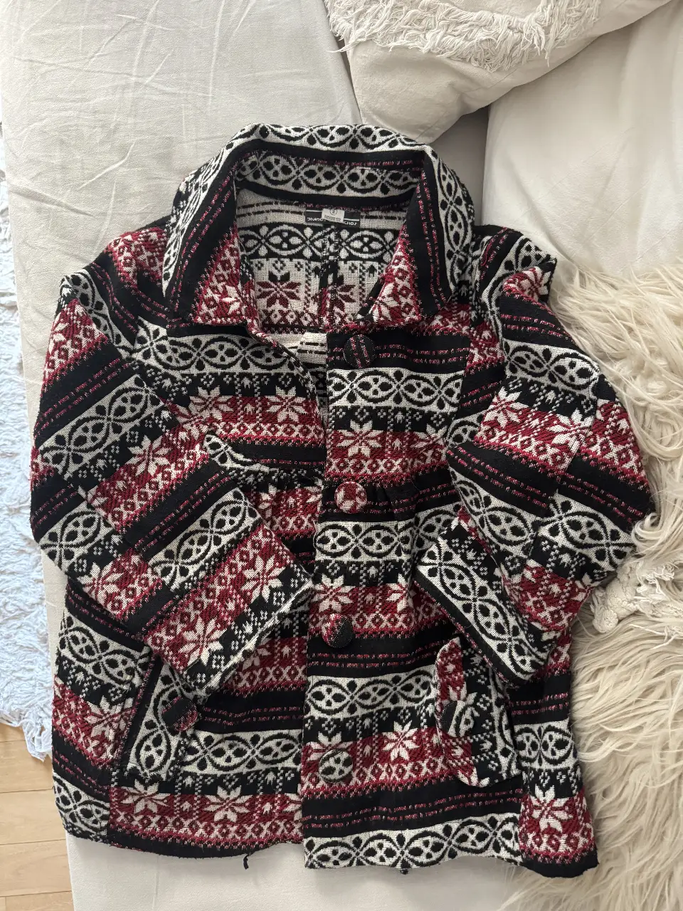 Cardigan tejido con diseño de copos de nieve y patrones geométricos en rojo, blanco y negro. Ideal para un look vintage y abrigado.