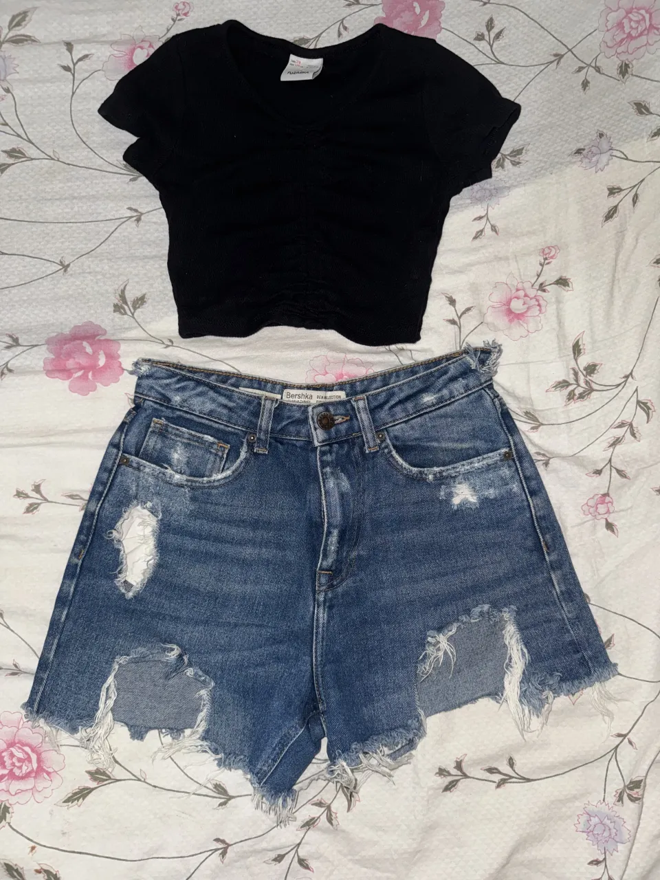 Conjunto de remera negra manga corta con fruncido y shorts de jean tiro alto con roturas y detalles desflecados. Ideal para un look casual y moderno.