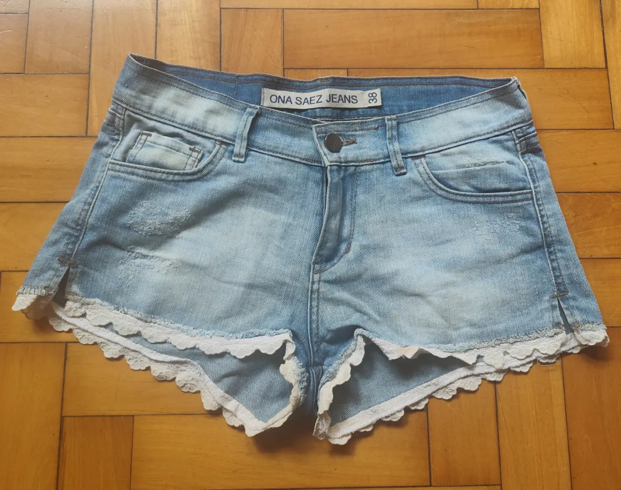 Short de jean de mujer, tiro medio, con detalles de encaje blanco en el borde inferior. Marca ONA SAEZ JEANS. Talle 38.