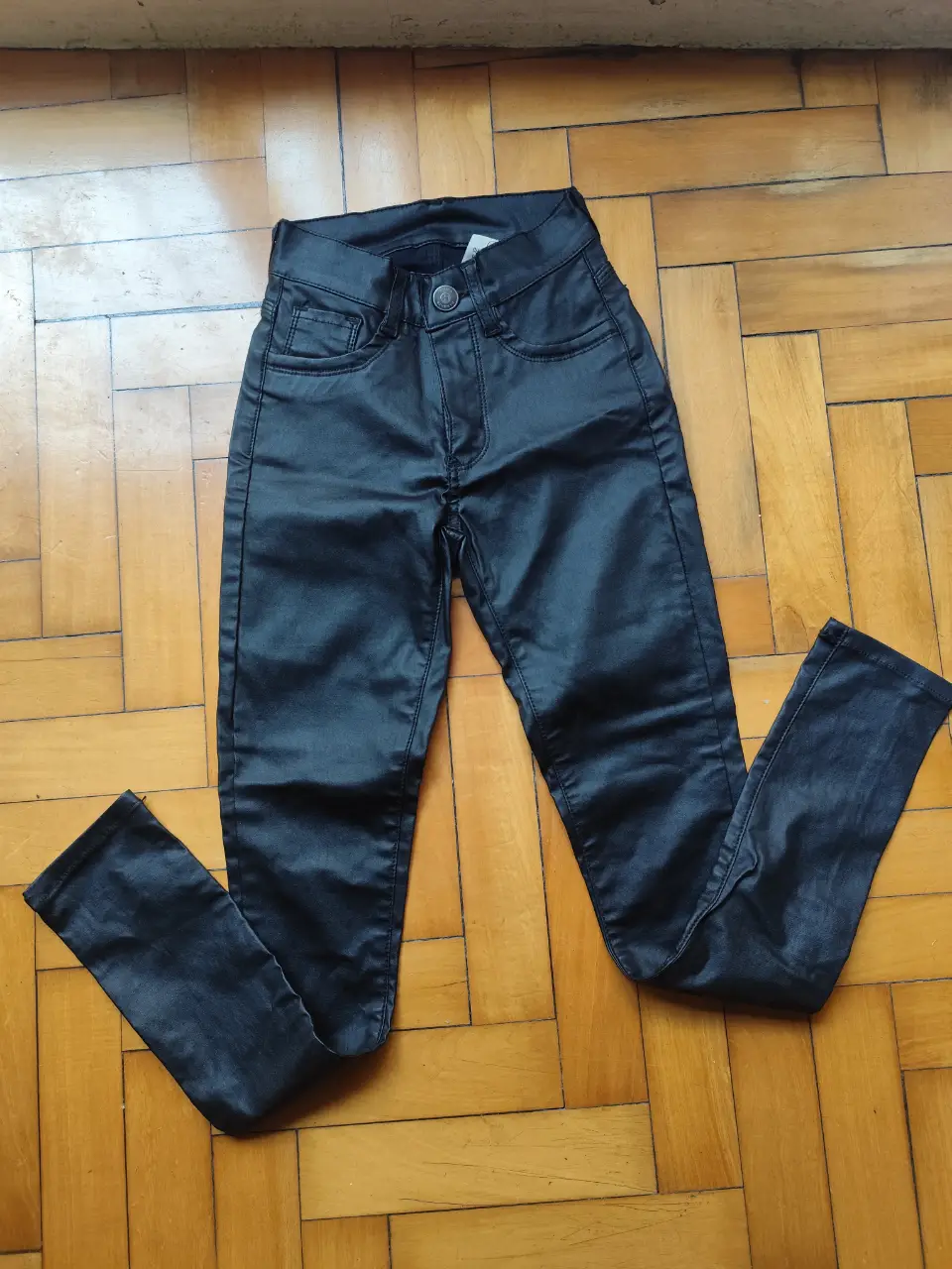 Pantalón negro de cuero sintético, tiro medio y chupín. Ideal para un look moderno y versátil. Talle Small 34/36