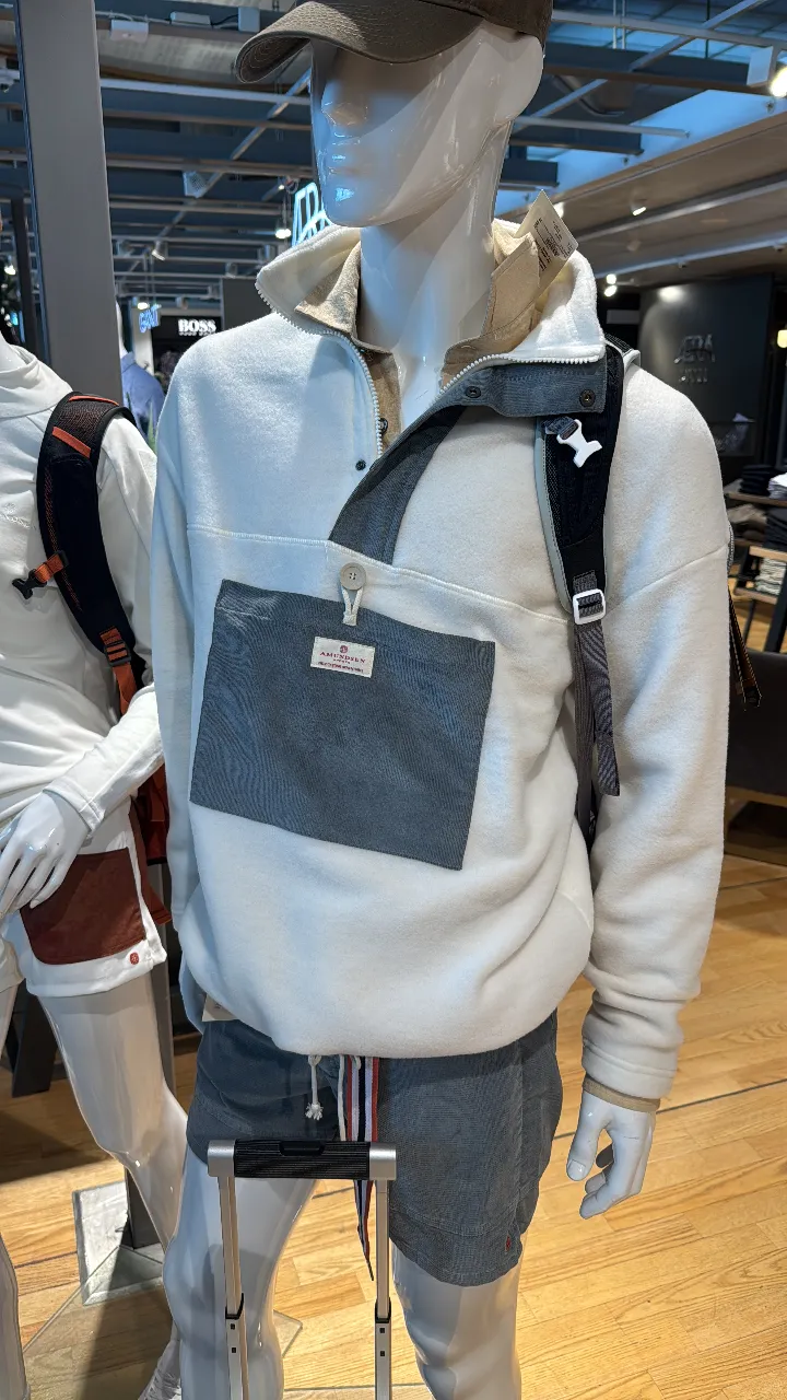 Buzo tipo pullover para hombre, de color blanco con un bolsillo frontal gris oscuro. Cuello alto con botones y detalles en color crema. Ideal para un look casual y abrigado.
