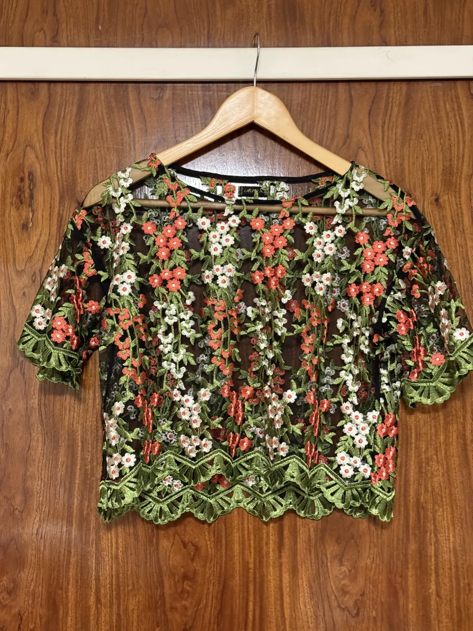 Remera crop de manga corta con bordado floral en relieve. Posee cuello redondo y terminación con ondas en el borde inferior.