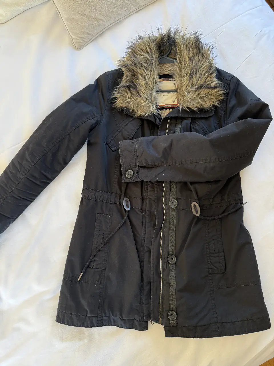 Campera negra con cuello de piel sintética. Posee cierre y botones, con ajuste en la cintura. Ideal para el invierno.