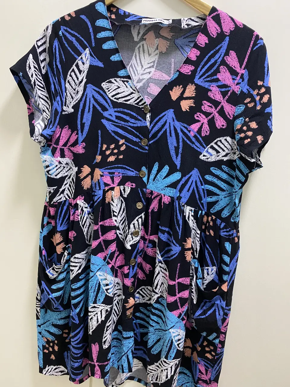 Vestido midi camisero con estampado floral en tonos vibrantes. Diseño con botones en la parte delantera, mangas cortas y bolsillos laterales. Ideal para un look fresco y casual. Talle 3/L. 