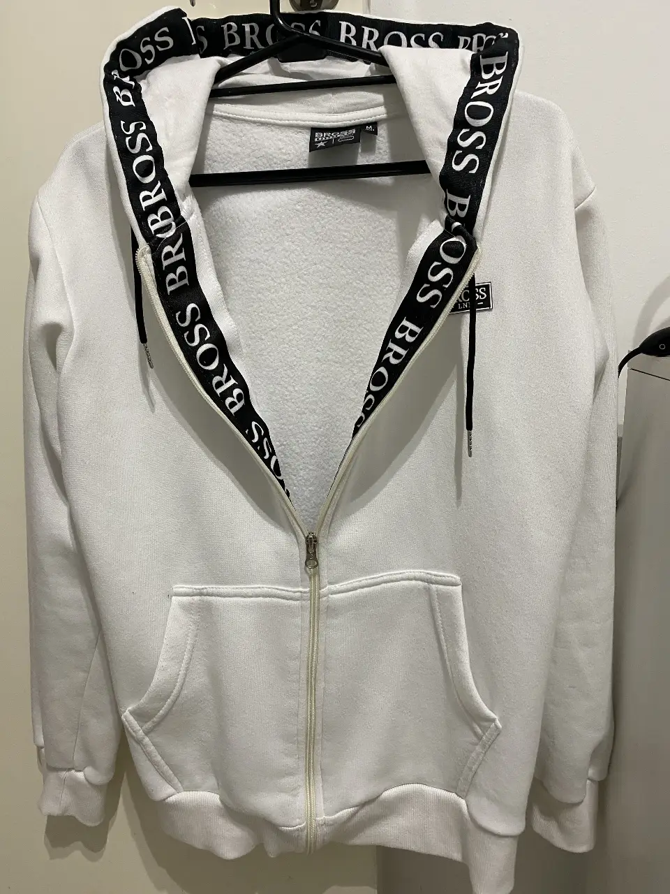 Buzo campera BROSS LONDON con cierre blanco con capucha y detalles en negro. Ideal para un look casual y cómodo. Talle M. 