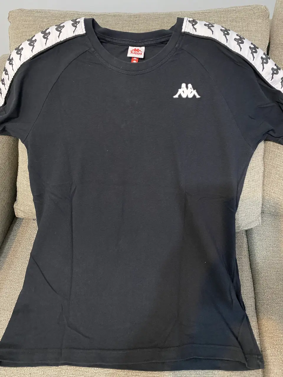 Remera Kappa negra con detalles blancos en las mangas. Cuello redondo y logo de la marca en el pecho. Talle M.