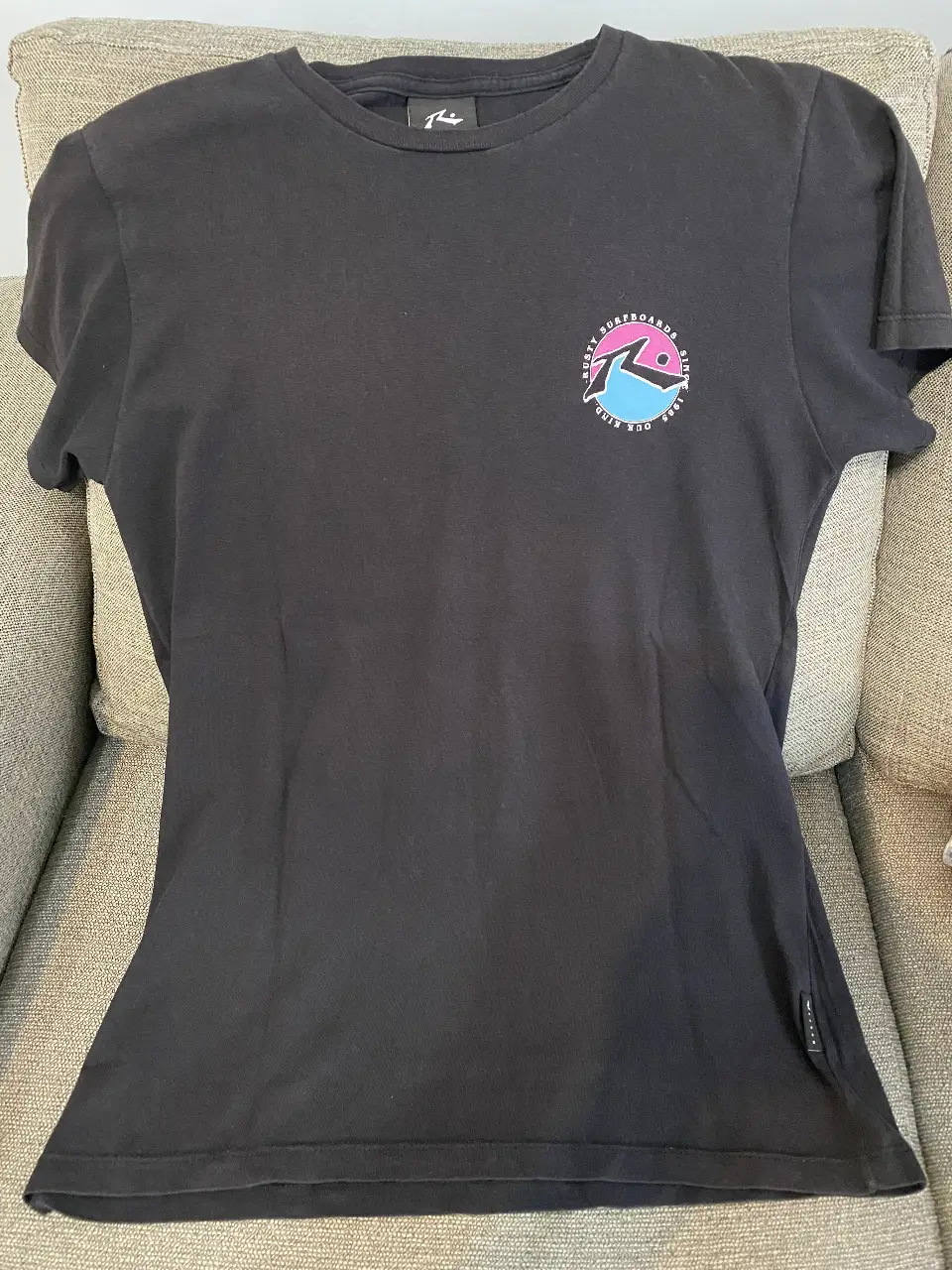 Remera negra de manga corta con estampado en el pecho y la espalda de la marca Rusty. Ideal para un look casual y urbano. Talle 16. 