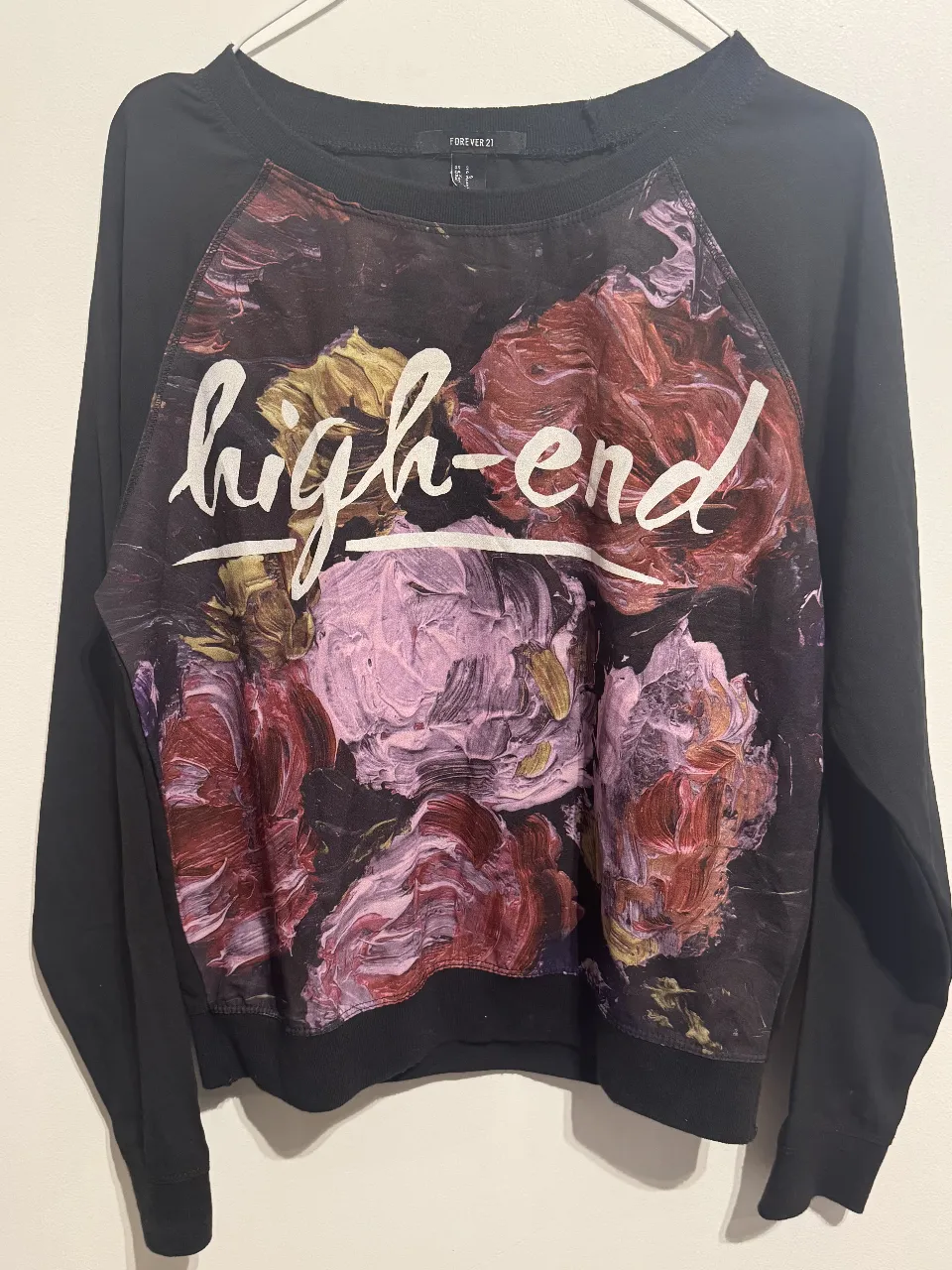 Buzo de cuello redondo para mujer, con estampado floral "high-end" en el frente. Mangas largas negras y corte clásico. Ideal para un look casual y moderno.
