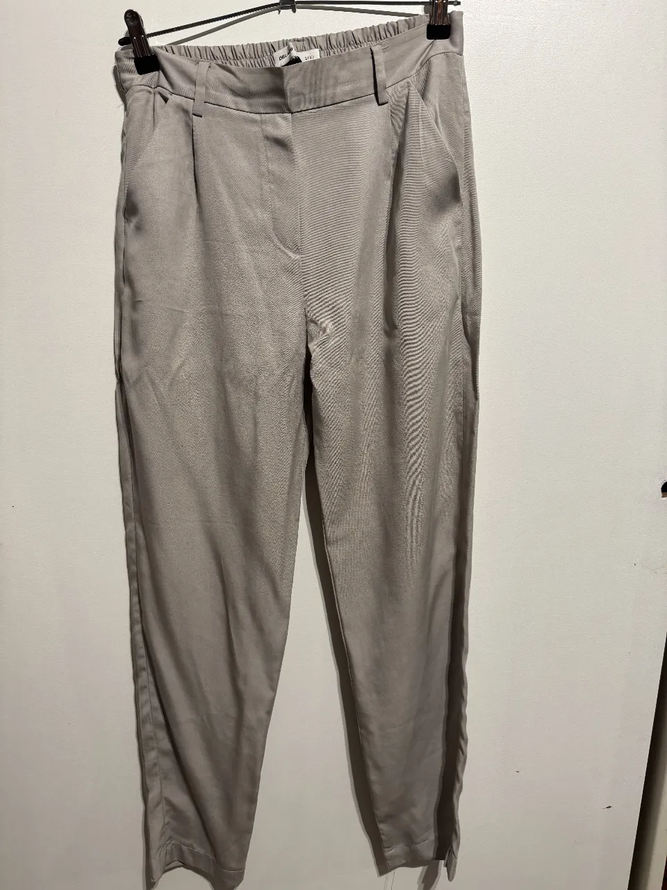 Pantalón sastrero de mujer, color gris, con pinzas y corte recto. Ideal para un look elegante y sofisticado.