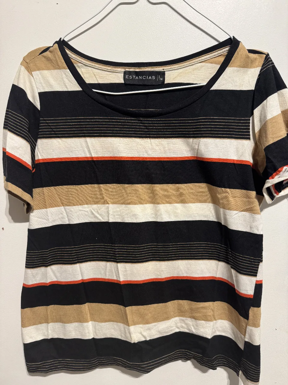 Remera a rayas horizontales, con detalles en naranja y beige. Cuello redondo. Ideal para un look casual y cómodo.