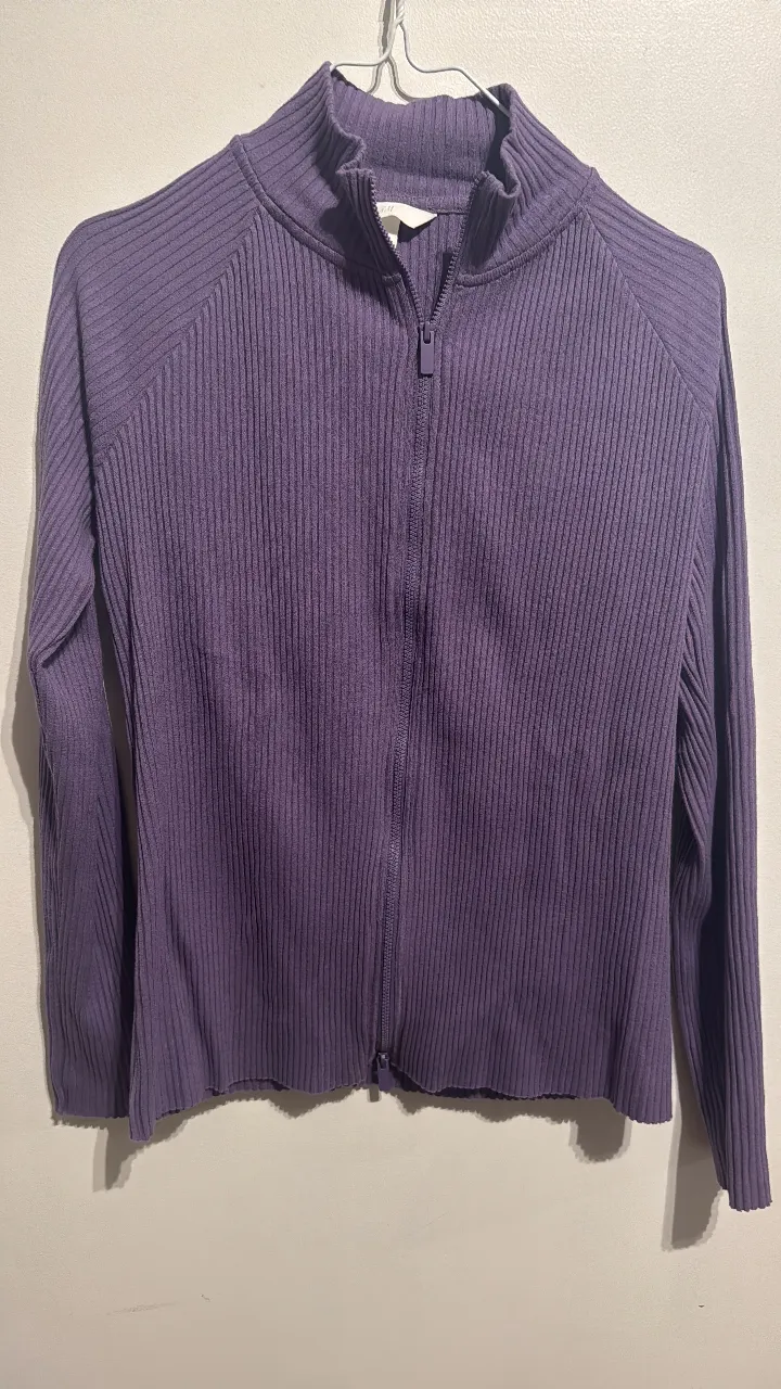 Sweater de mujer con cierre y cuello alto en color violeta. Tejido de punto acanalado, ideal para un look casual y abrigado.