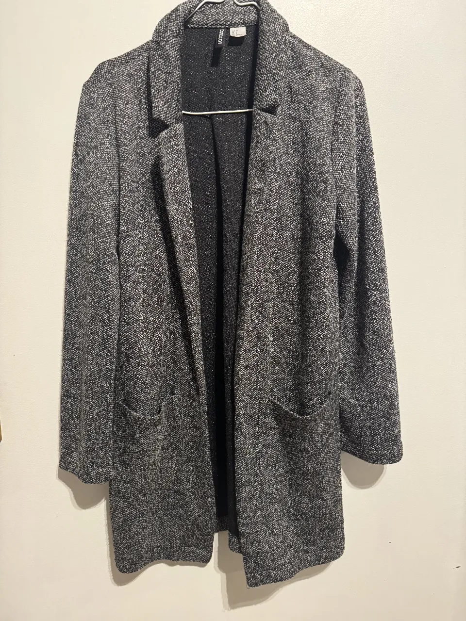 Blazer de mujer, color gris con diseño de tejido. Posee dos bolsillos delanteros y solapas clásicas. Ideal para un look elegante y versátil.