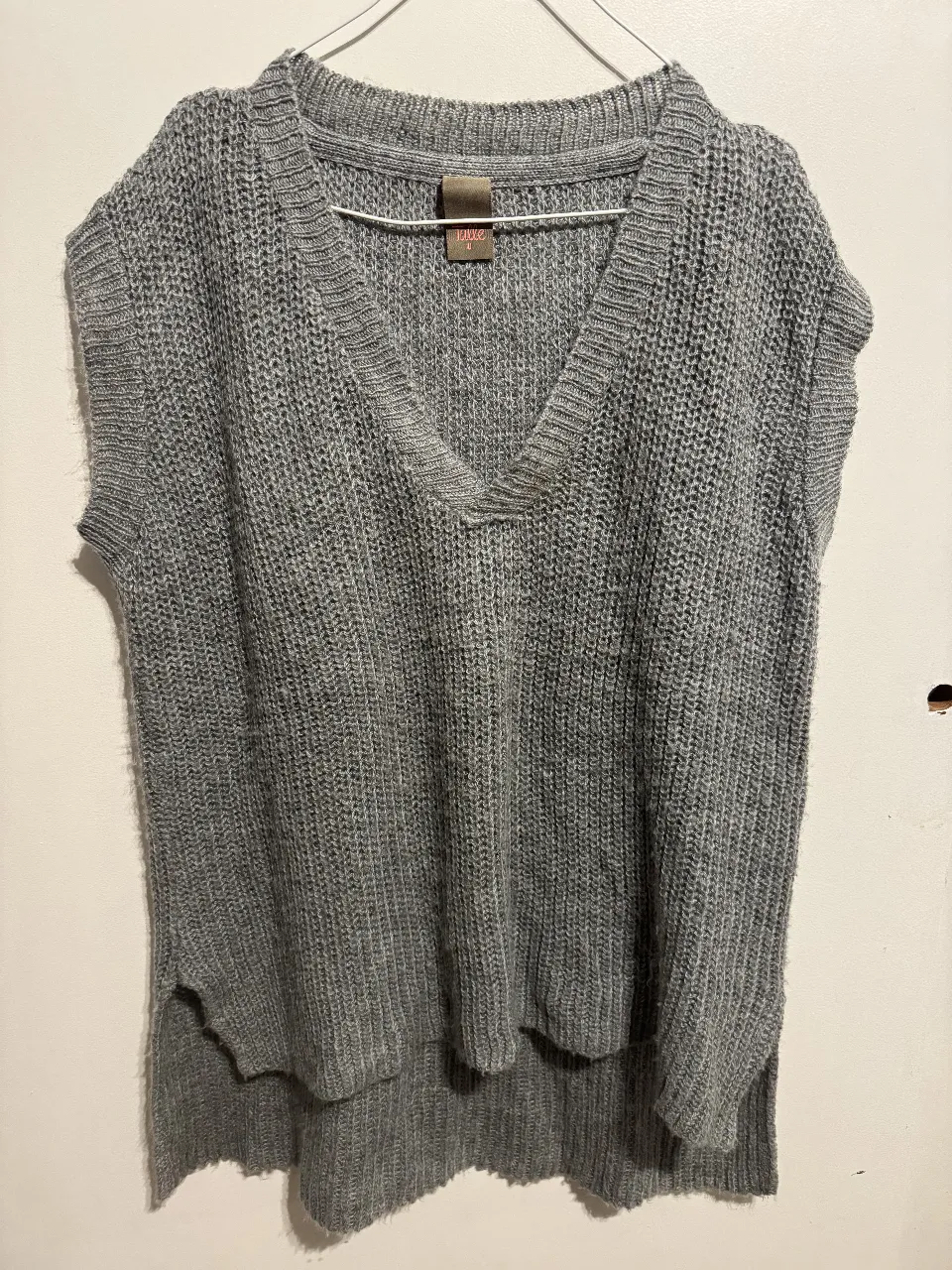 Chaleco de punto gris con cuello en V y diseño sin mangas. Ideal para un look casual y moderno. Tiene una pequeña mancha en el escote. 