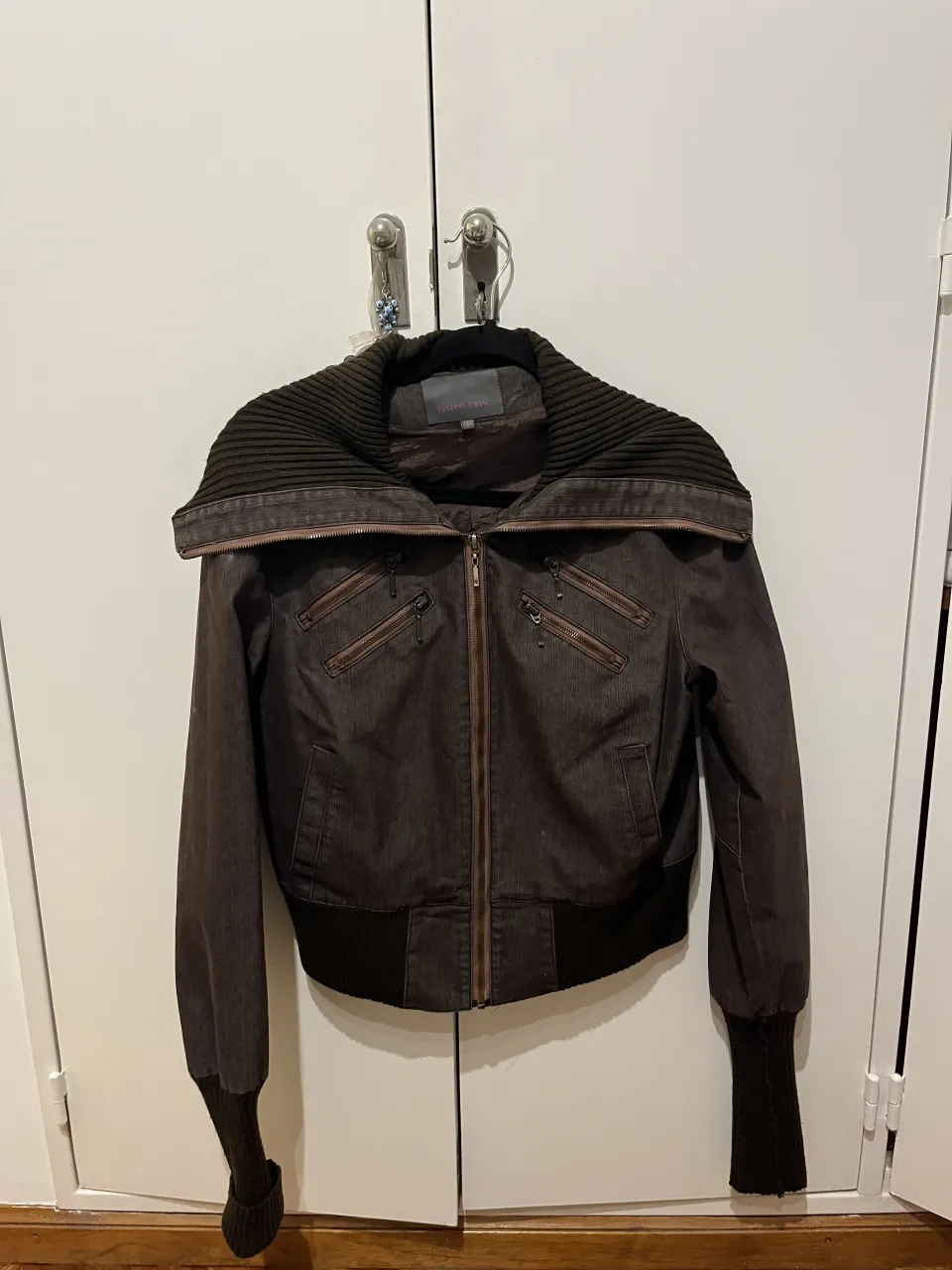 Campera corta con cuello ancho de tela acanalada. Cierre central y bolsillos frontales con cierre. Puños y cintura elastizados.