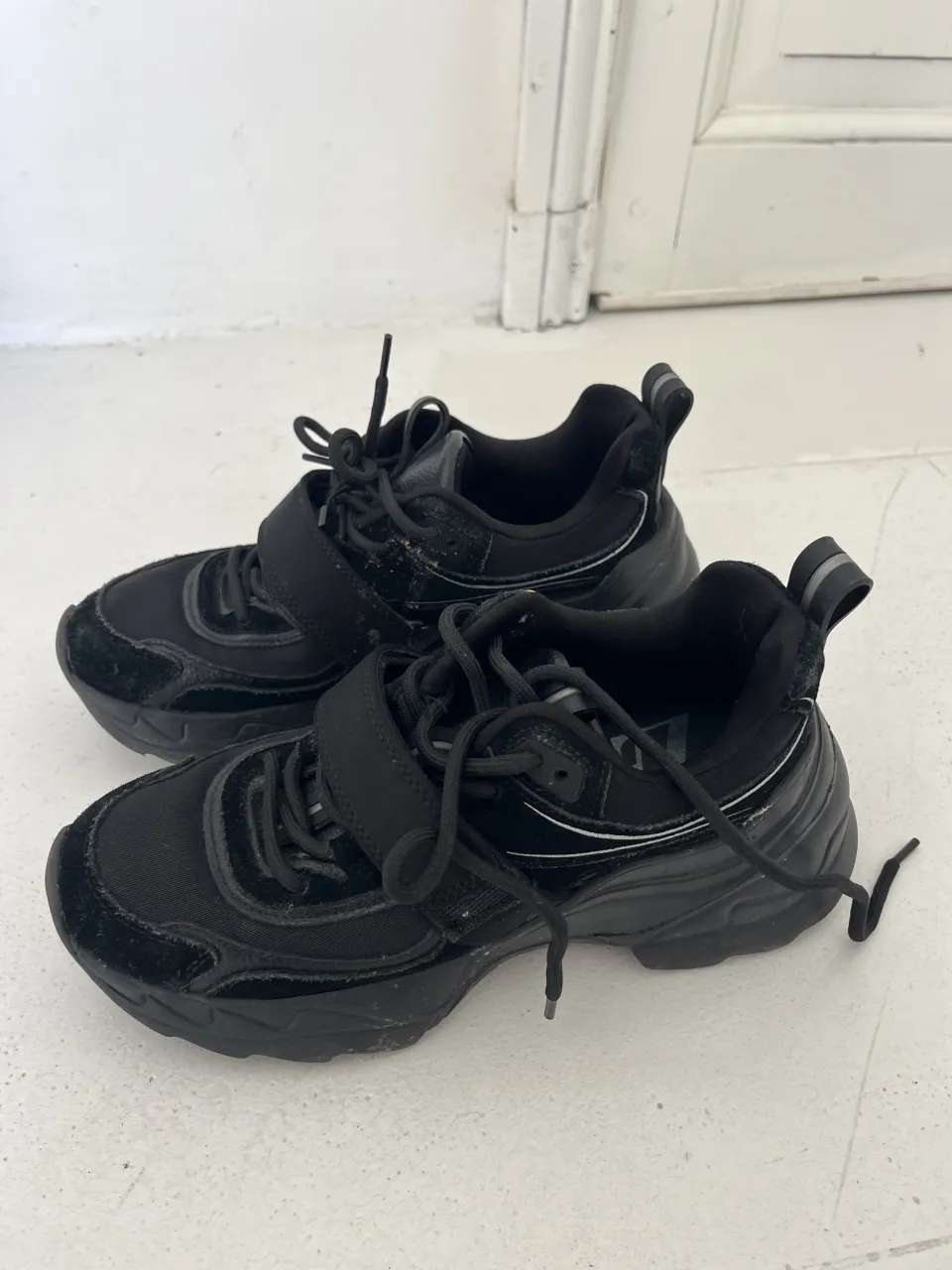Zapatillas deportivas negras con cordones y velcro.