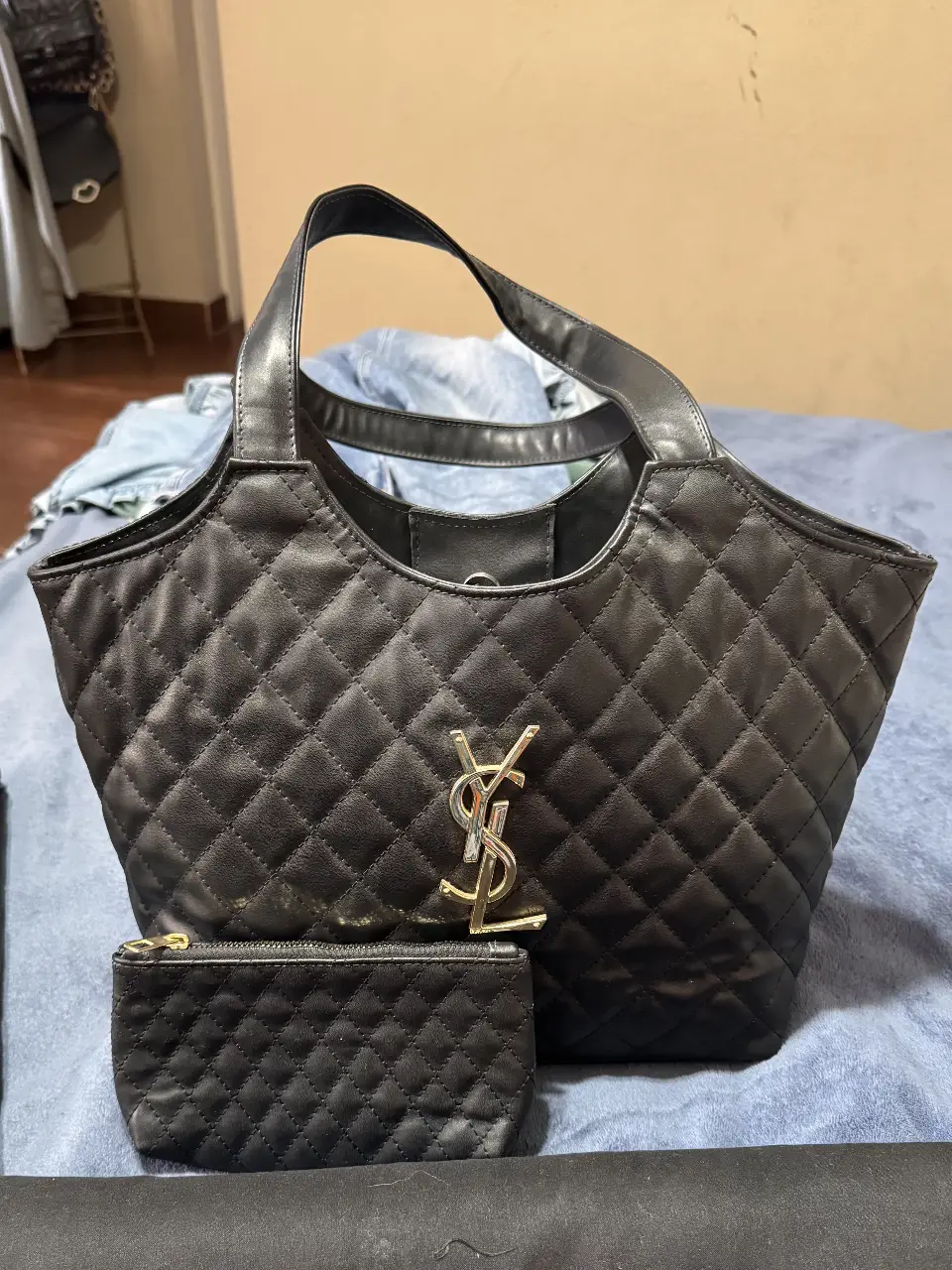 Cartera negra acolchada con logo YSL plateado. Incluye un pequeño monedero a juego. Ideal para un look elegante y sofisticado.