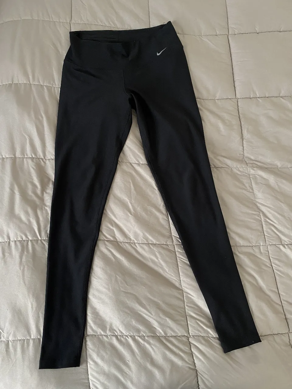Calzas deportivas negras de la marca Nike, talle S. Confeccionadas en una mezcla de poliéster y elastano, ideales para actividades físicas. Poseen el logo de la marca en la cintura.