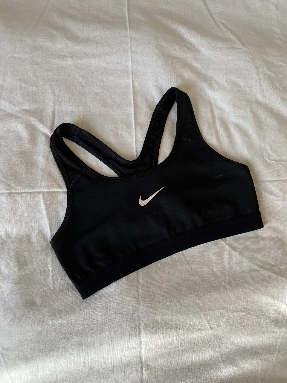 Top deportivo Nike negro, ideal para entrenamientos de alto impacto. Confeccionado con tejido Dri-FIT para mantener la frescura y comodidad. Logo de la marca en blanco.