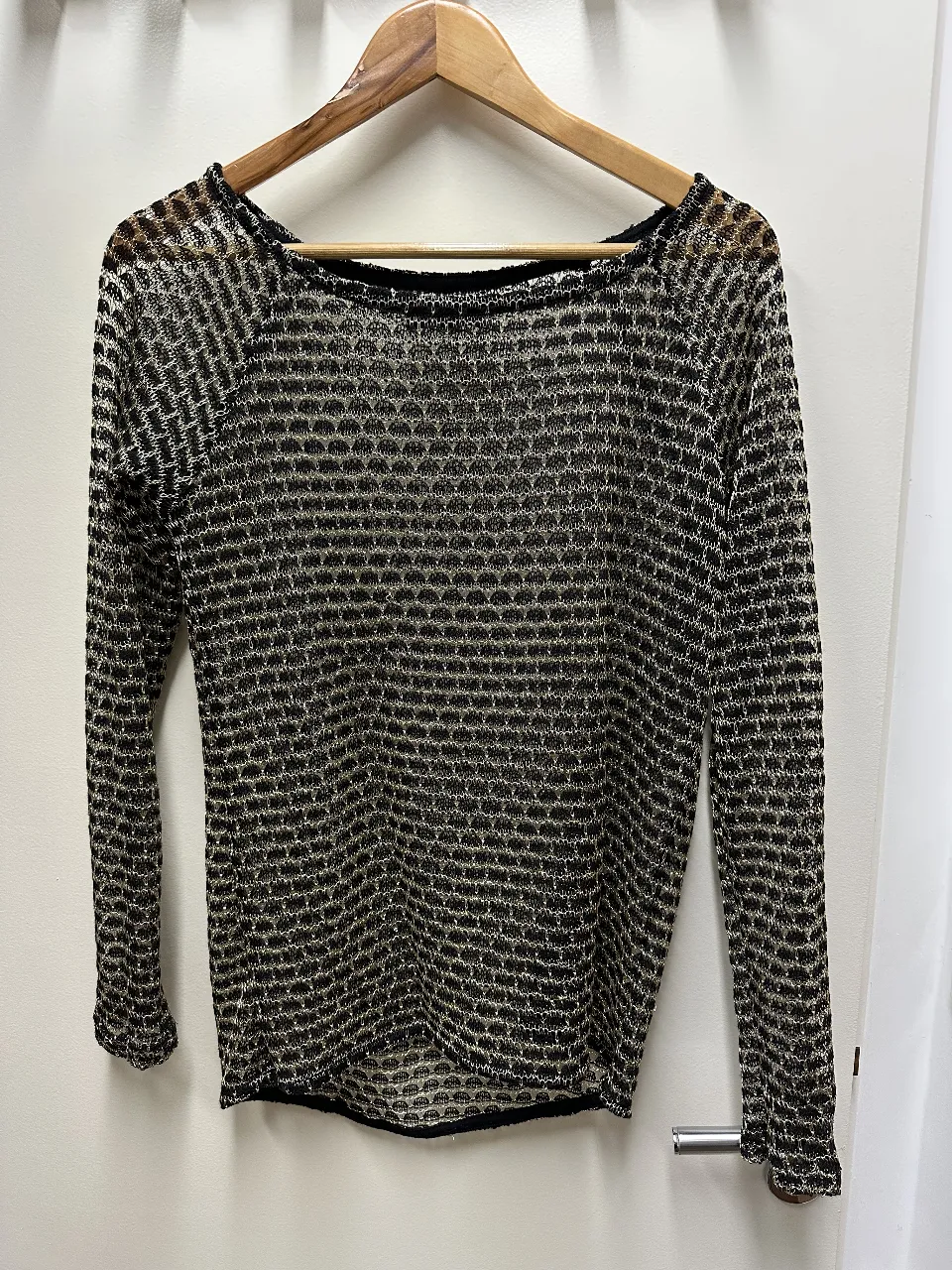 Remera de manga larga de red con diseño calado en color negro y dorado. Ideal para un look sofisticado y moderno.