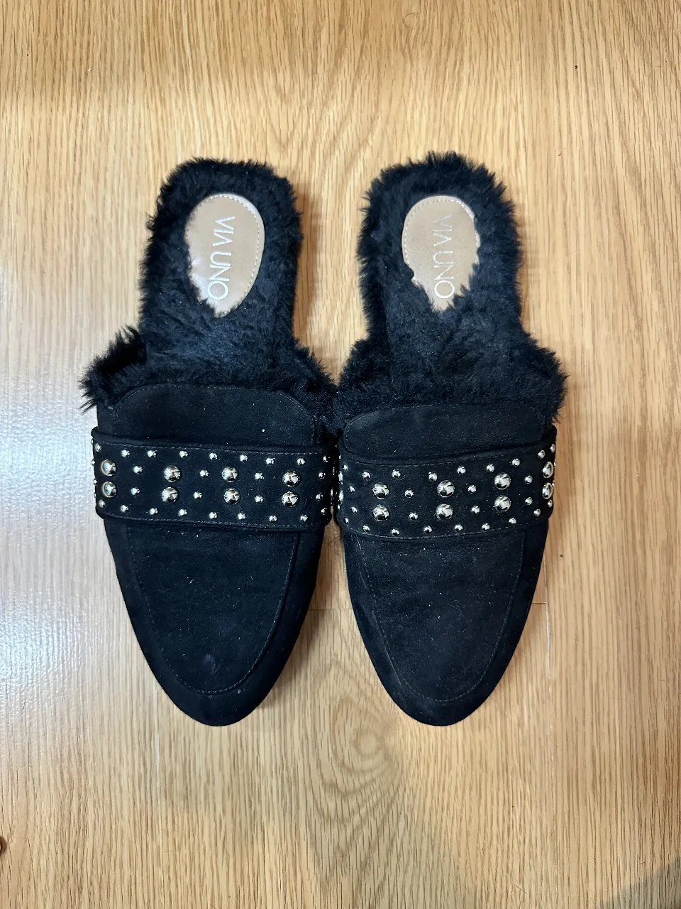 Zuecos negros de gamuza con detalle de tachas plateadas y forro de piel sintética. Ideales para un look moderno y abrigado.