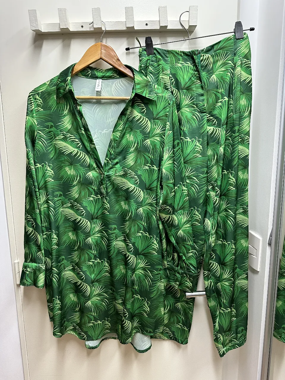 Conjunto de camisa y pantalón estampado con hojas tropicales. La camisa es de manga larga con botones y el pantalón es de corte recto. Ideal para un look fresco y moderno.