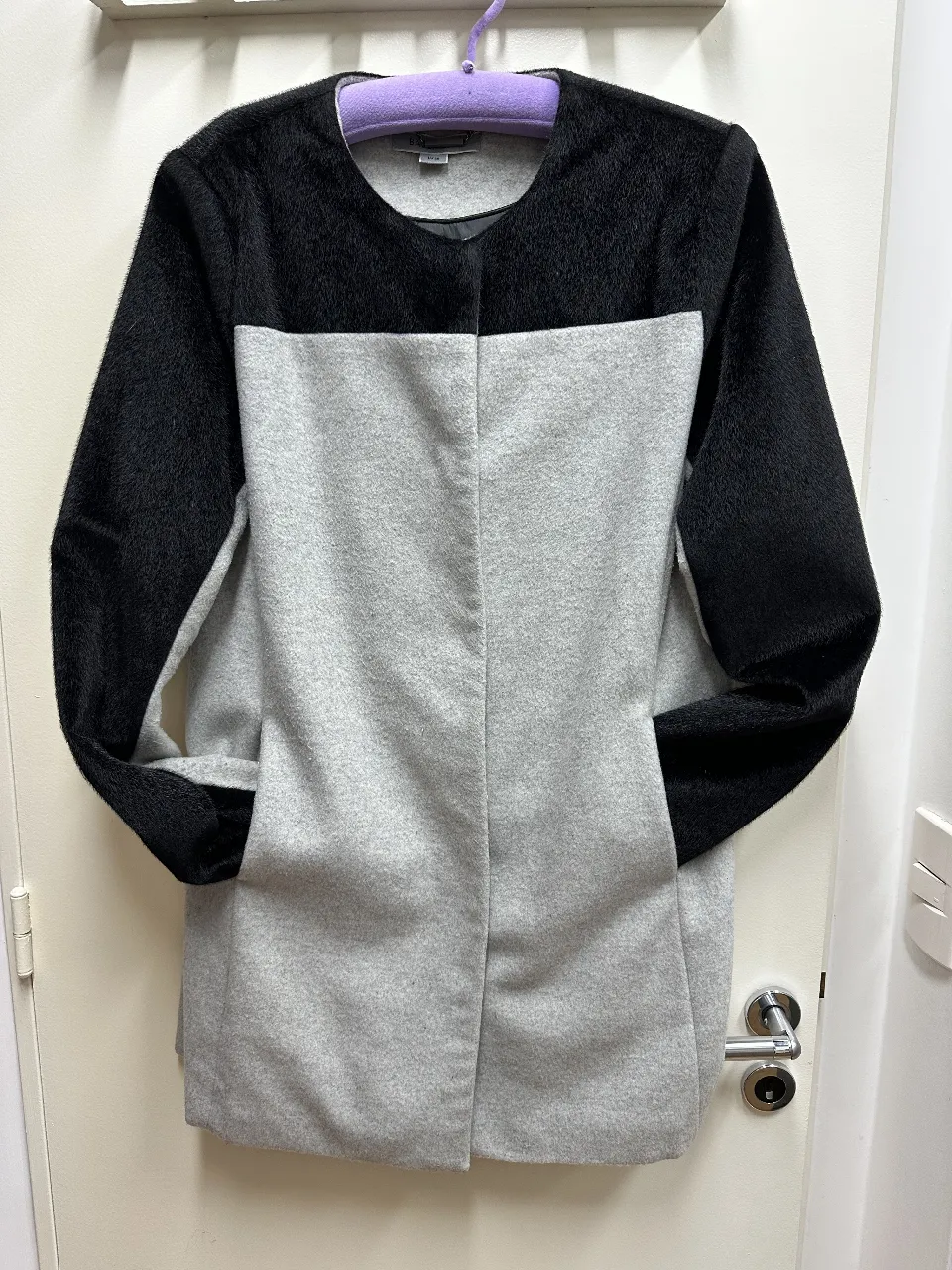 Sobretodo de paño para mujer, con diseño bicolor en gris y negro. Posee mangas largas y bolsillos laterales. Ideal para el invierno.