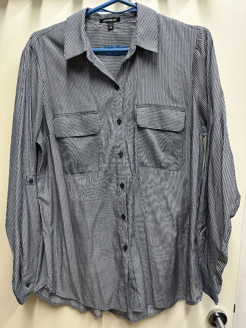 Camisa de mujer a rayas azul y blanca de la marca Express, con dos bolsillos delanteros. Ideal para un look casual o de trabajo.
