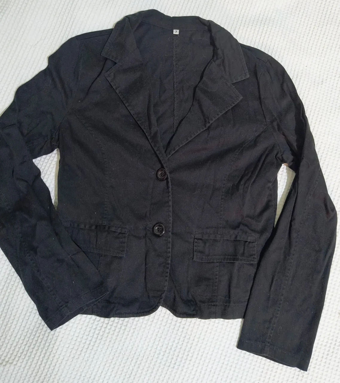 Blazer negro de corte clásico, ideal para un look elegante y formal. Cuenta con dos botones al frente y bolsillos con solapa. 