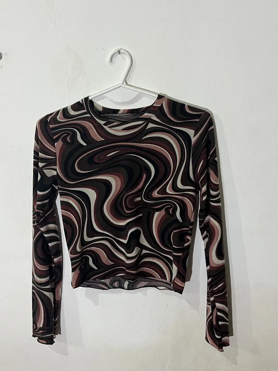 Remera manga larga al ombligo con estampado psicodélico en tonos bordo ,marron , blanco y negro. Ideal para un look retro y moderno.