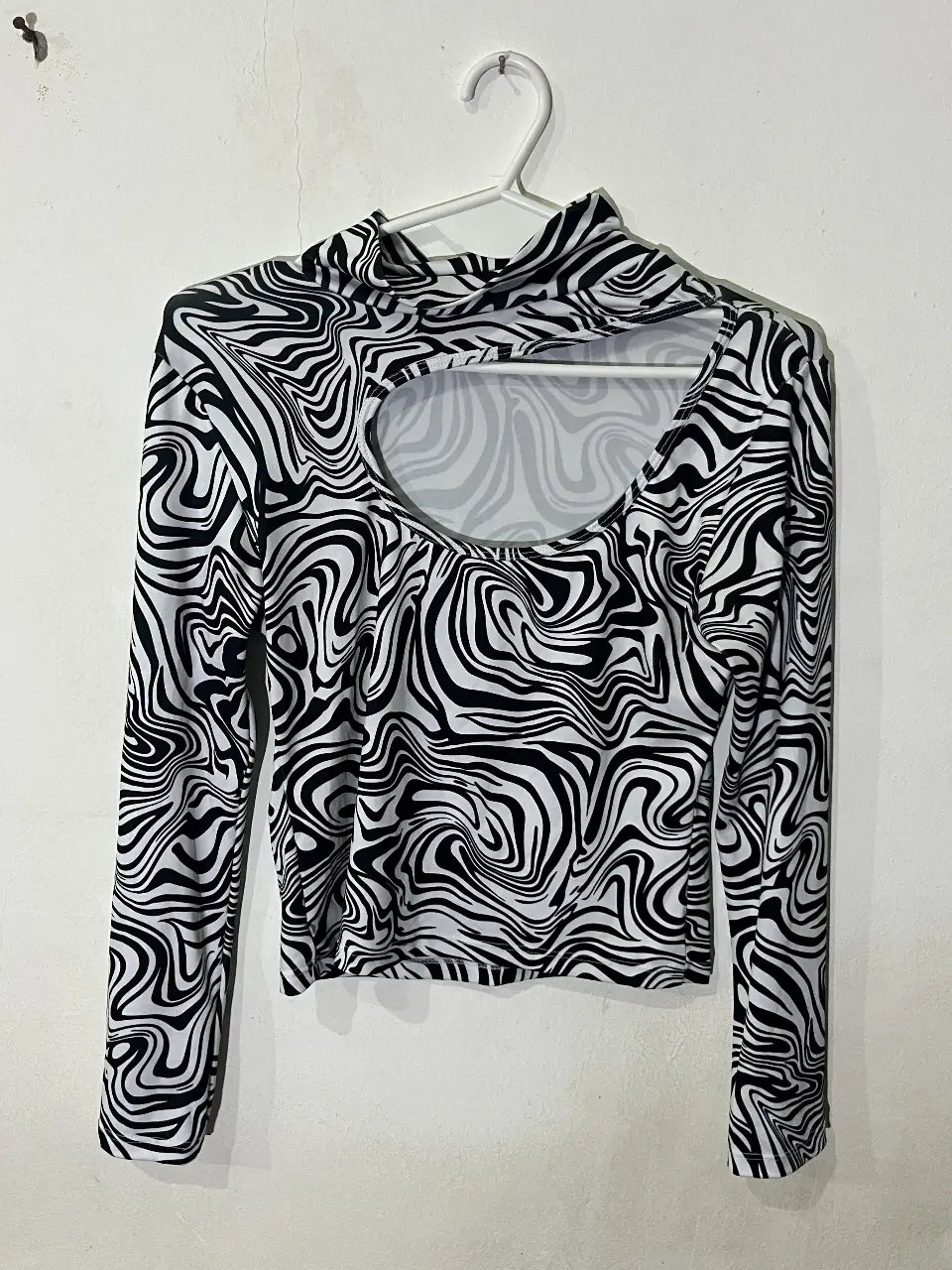 Remera manga larga con estampado de diseño abstracto en blanco y negro. Cuello alto con abertura en el pecho. Talle M