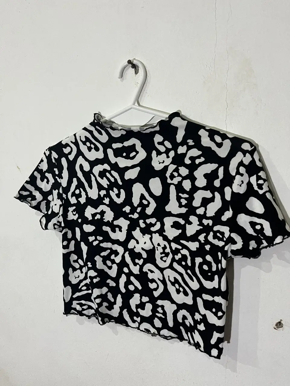 Top de mujer con estampado de leopardo en blanco y negro. Cuello alto y mangas cortas con terminación ondulada. Talle S