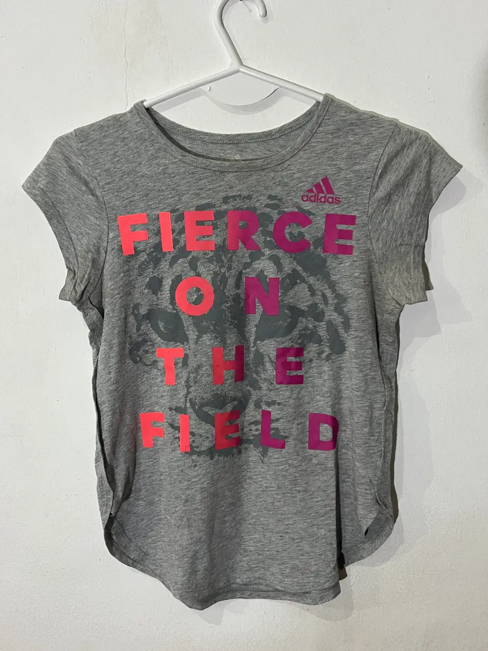Remera deportiva Adidas gris con estampado "FIERCE ON THE FIELD" en rosa. Ideal para entrenar!