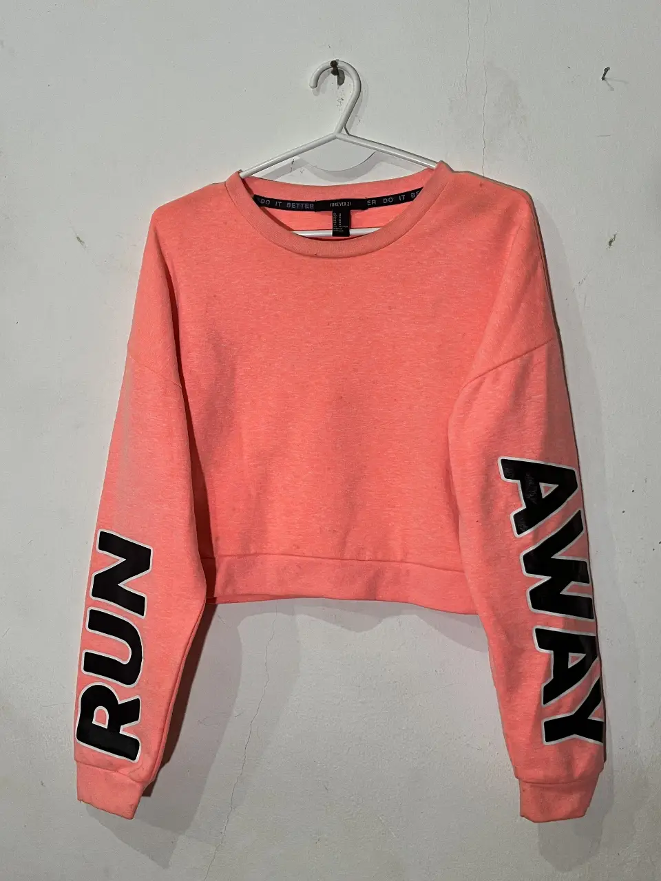 Buzo de cuello redondo color rosa con mangas largas. En las mangas tiene la palabra "RUN" y "AWAY" en color negro. Es de la marca Forever 21 y talle M.