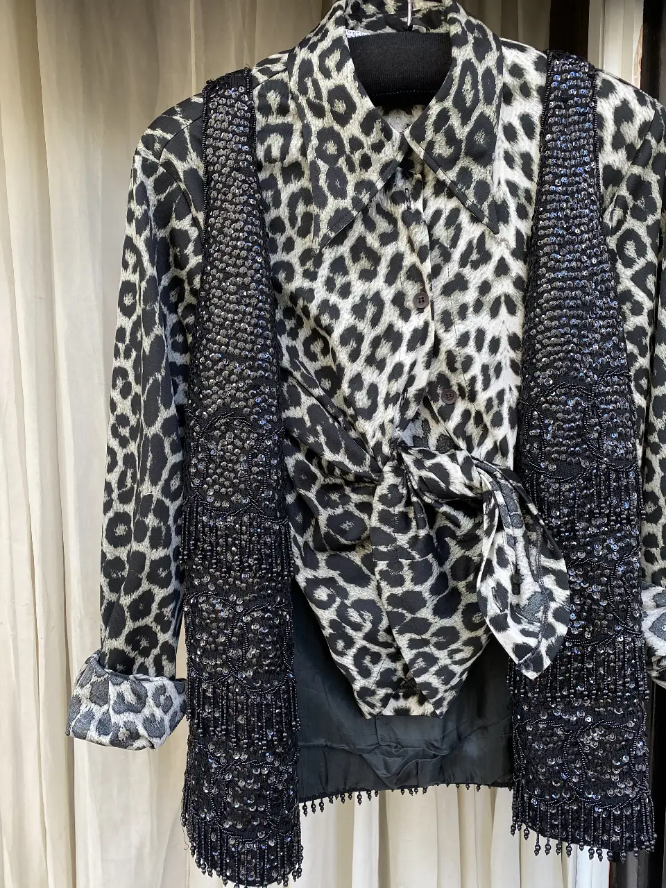 Camisa estampada con diseño de leopardo, con un chaleco negro con lentejuelas. Ideal para un look audaz y sofisticado.